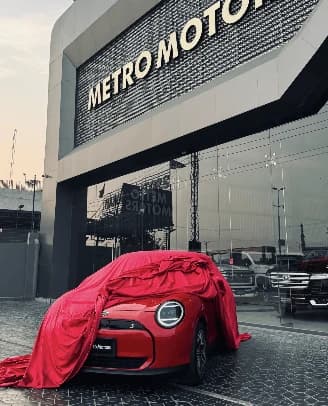 A car under a red cover, ready for its unveiling outside the Metro Motors showroom